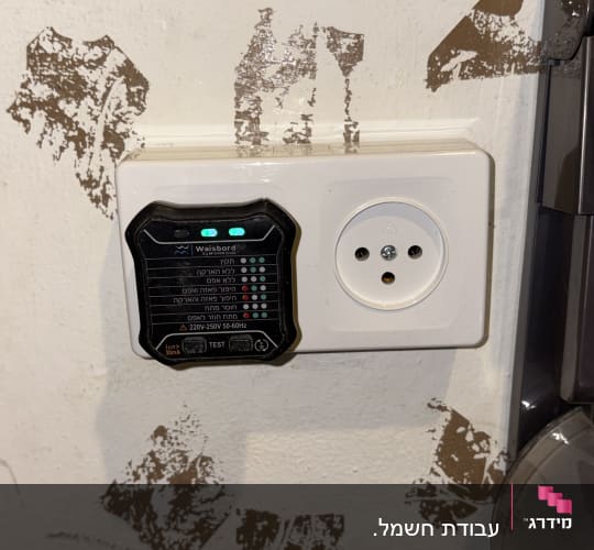 שקע חשמלי עם בודק תקינות מחובר לקיר